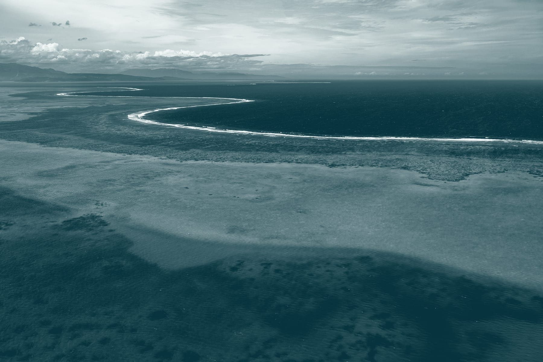 La barrière de corail vue d’avion : une ligne d’écume sépare le lagon de l’océan.