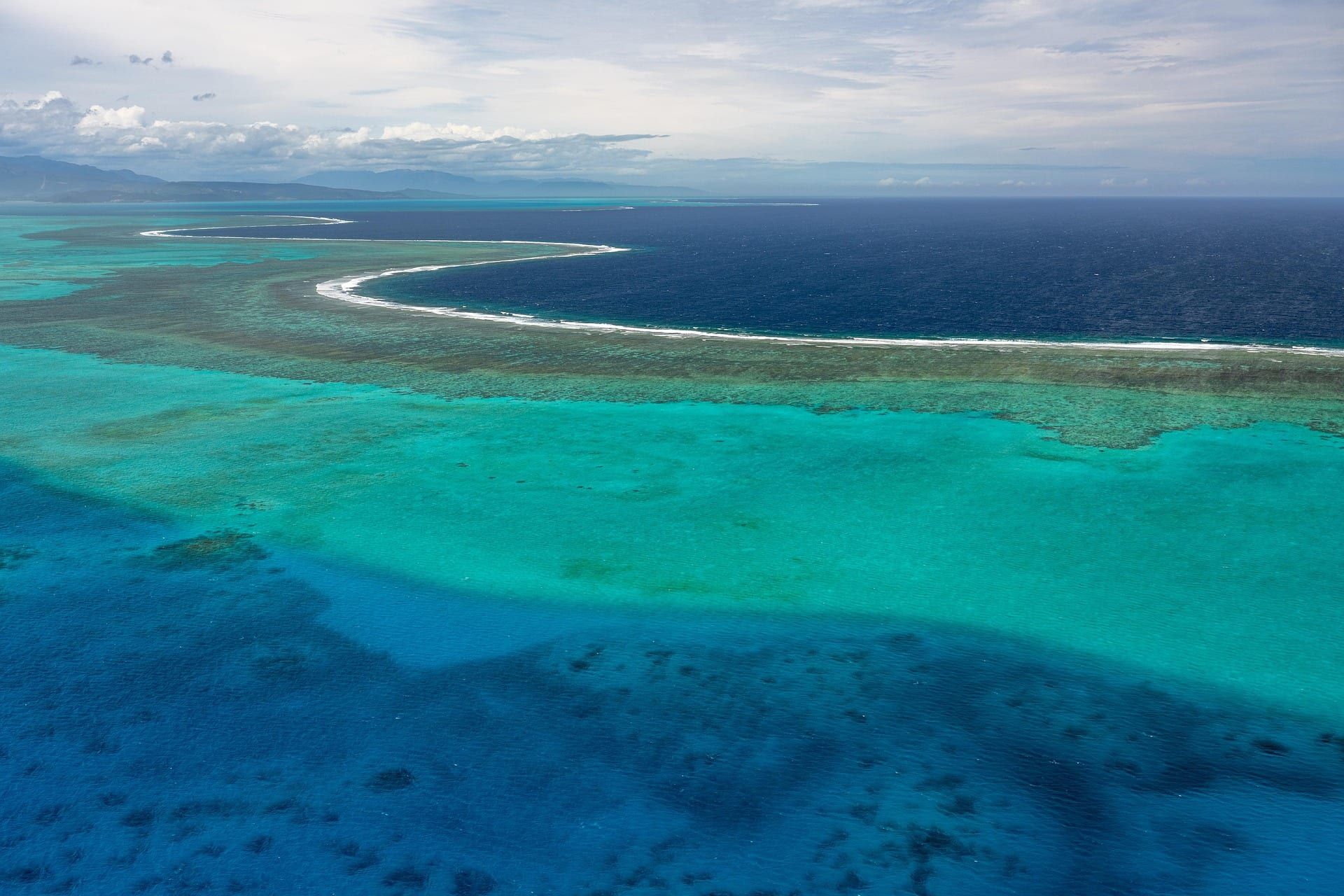 La barrière de corail vue d'avion : une ligne d'écume sépare le lagon de l'océan.