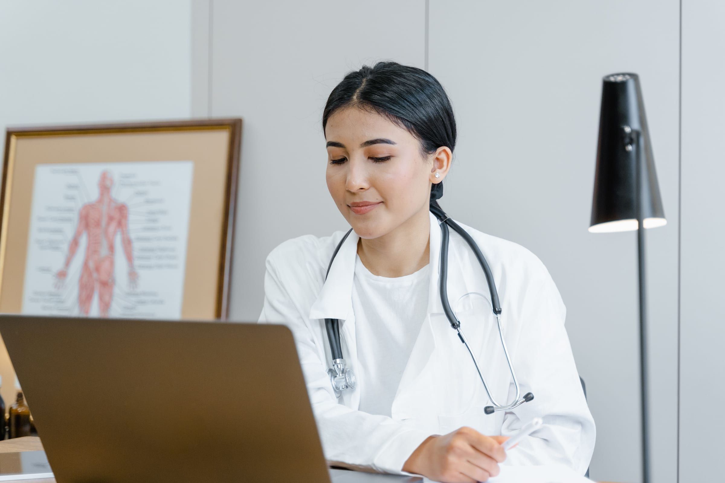Une médecin prend des notes à son bureau de consultation.