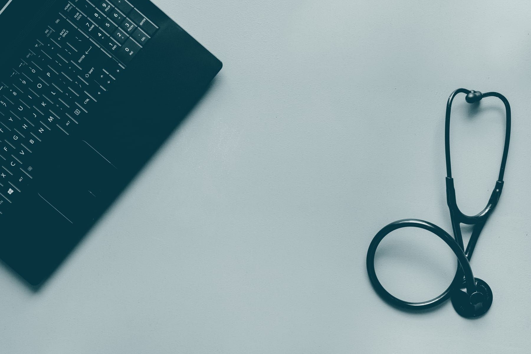 Un ordinateur portable et un stéthoscope posés sur un plan de travail.